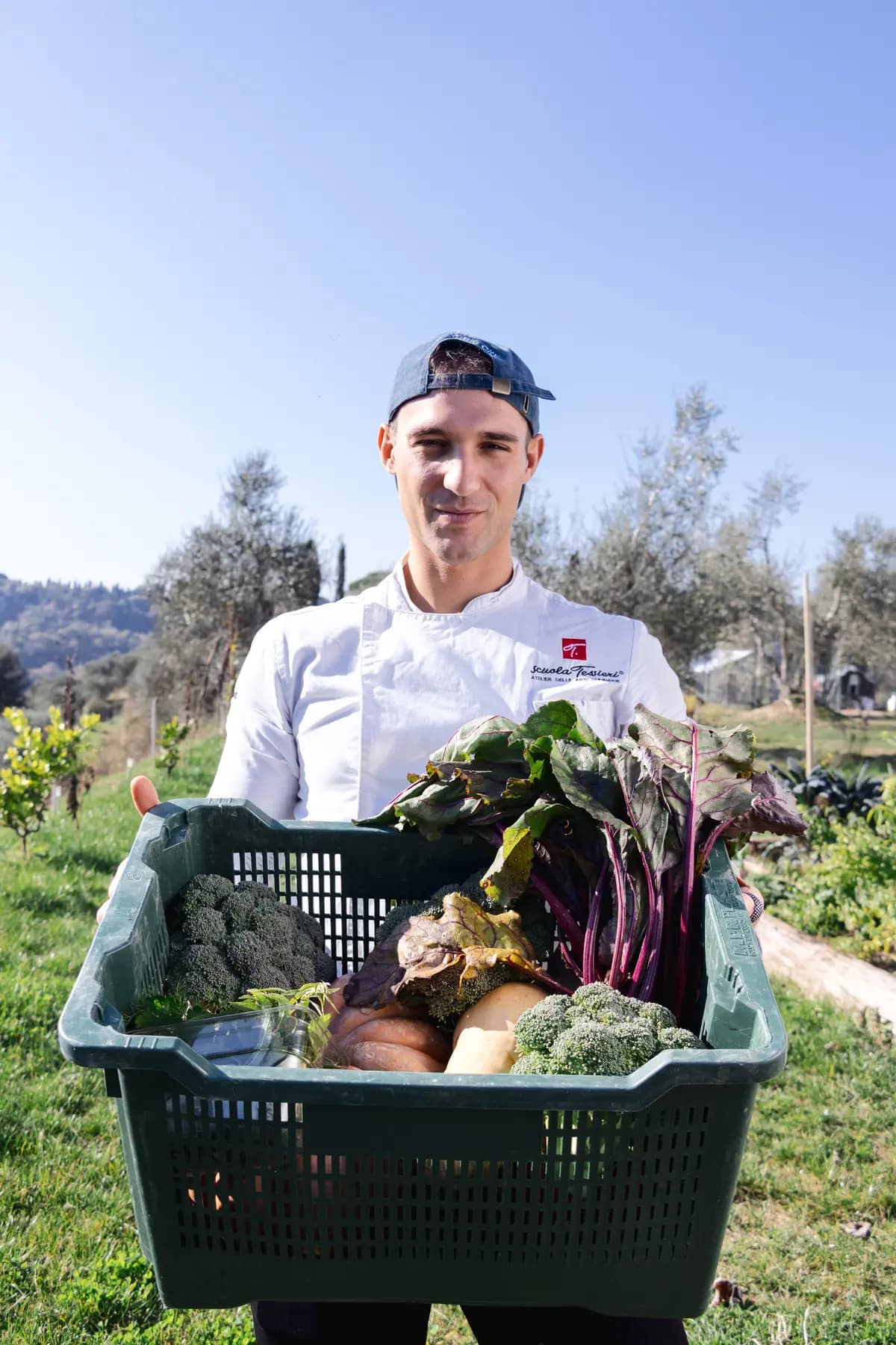 Simone Dragoni con la cassetta delle verdure in piedi all'aperto